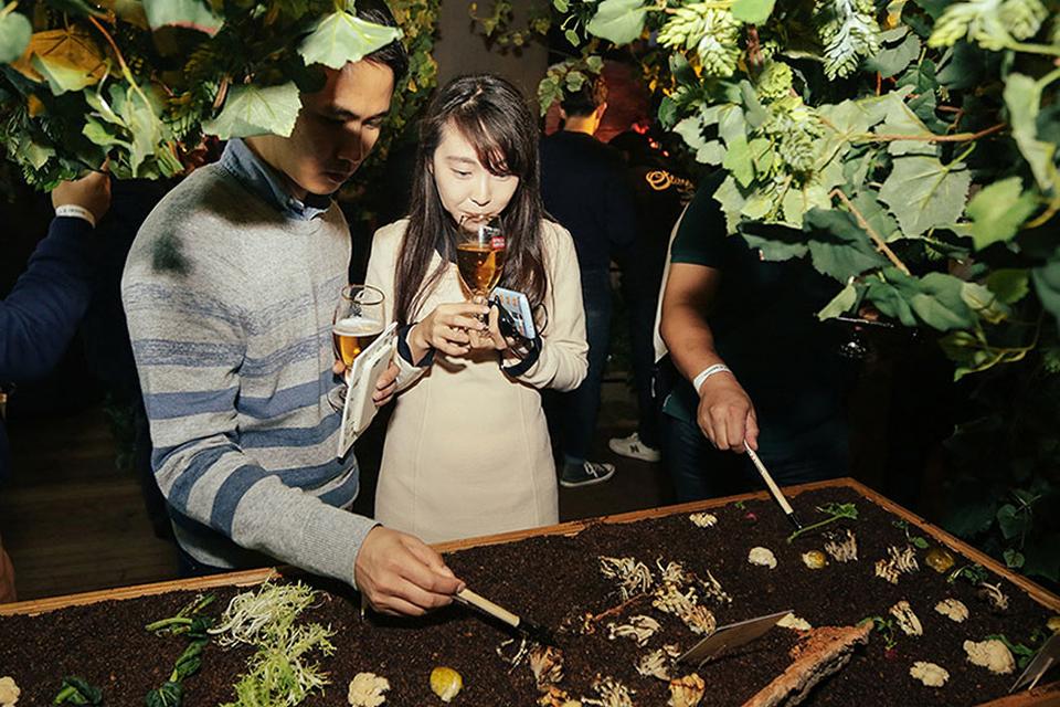 Guests interact with a soil-based tasting installation while sampling drinks at a Cirque du Soleil experiential food event.